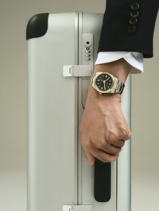 Man's hand holding white leather Hermès bag wearing Sweet Alhambra watch by Van Cleef & Arpels
