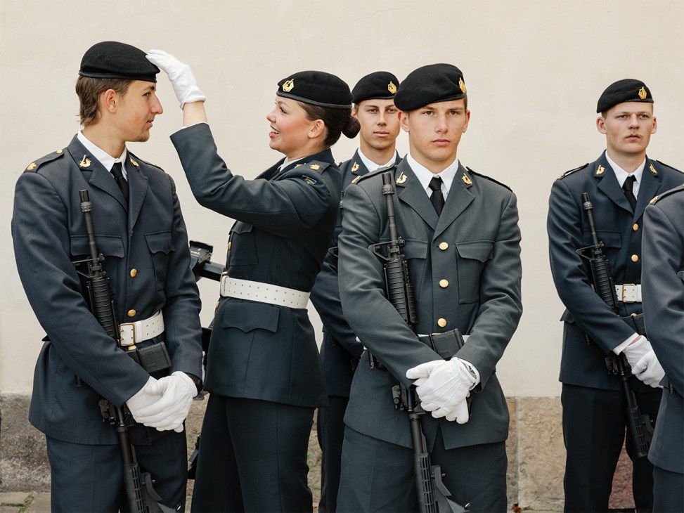 Swedish Army Band members in gunmetal-grey dress uniforms with rifles and white gloves standing in formation.