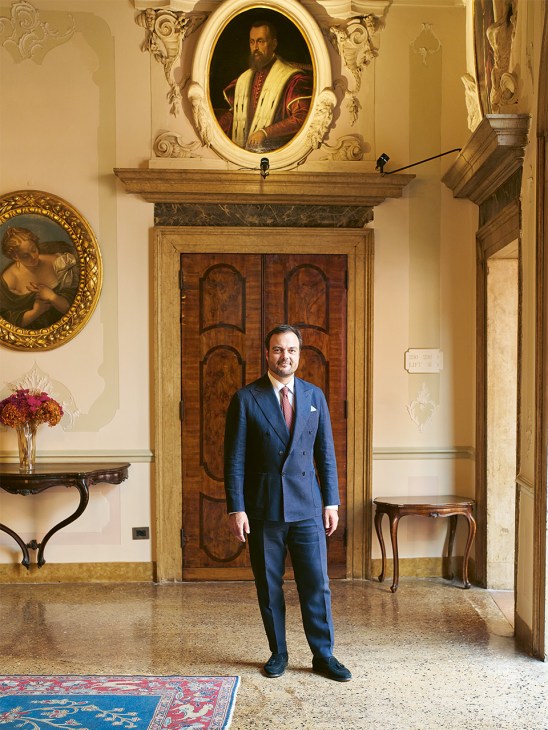 Christian Zandonella, general manager of the Danieli hotel, stands in an ornate Venice palazzo hallway wearing a blue suit.