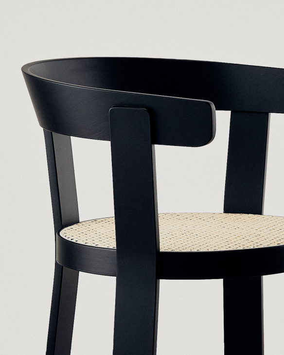 Black wooden chair with woven rattan seat designed by Teresa Kruszewska, photographed against a light background.