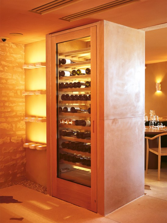 Illuminated wooden wine cooler displaying bottles of Burgundy wine on multiple shelves