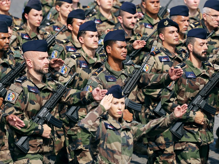 French soldiers in camouflage uniforms and berets stand in formation during the Bastille Day military parade in Paris.