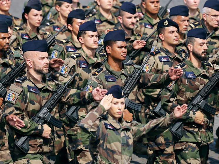 French soldiers in camouflage uniforms and berets stand in formation during the Bastille Day military parade in Paris.