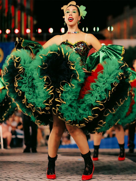 Performer in elaborate green and gold tulle costume with sparkly corset at Lisbon's Marchas Populares parade