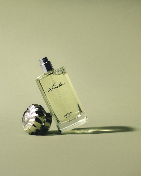 Moehr Sinclair perfume bottle with pale yellow liquid next to a decorative black and white flower-shaped object.