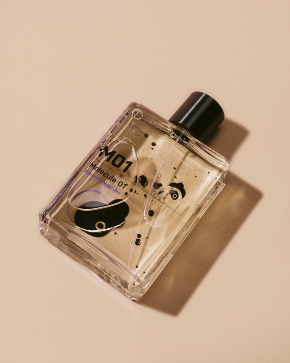 Escentric Molecules 01 perfume bottle with black cap on beige background.