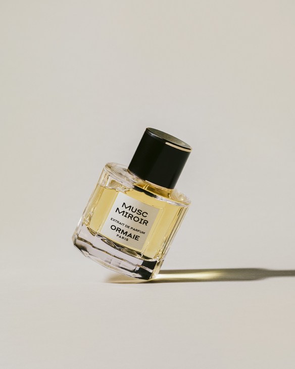 Ormaie Musc Miroir perfume bottle with pale yellow liquid and black cap on neutral background.