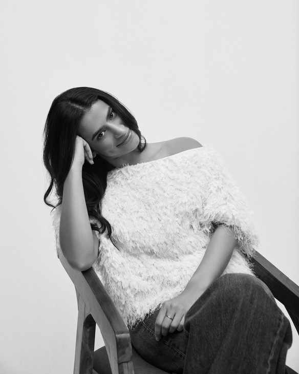 Black and white portrait of Priyanka Malhotra, founder and CEO of Heir fragrance, seated and wearing a textured white top.