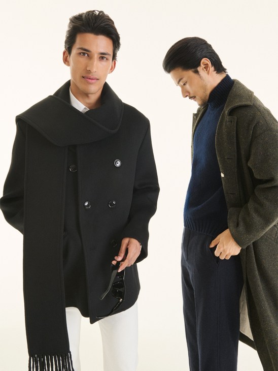 Two male models wearing autumn coats and knitwear from Toteme's menswear collection against a cream background.