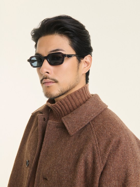 Man wearing brown Samuel Snider jacket and mock-neck jumper with black rectangular sunglasses