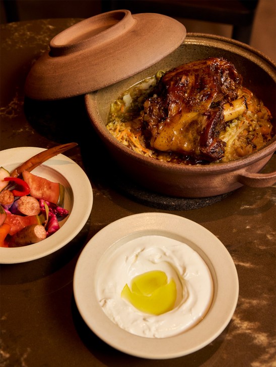 Braised goat shoulder with freekeh, fermented vegetables and chickpeas served in a terracotta pot with yoghurt and pickles on the side.