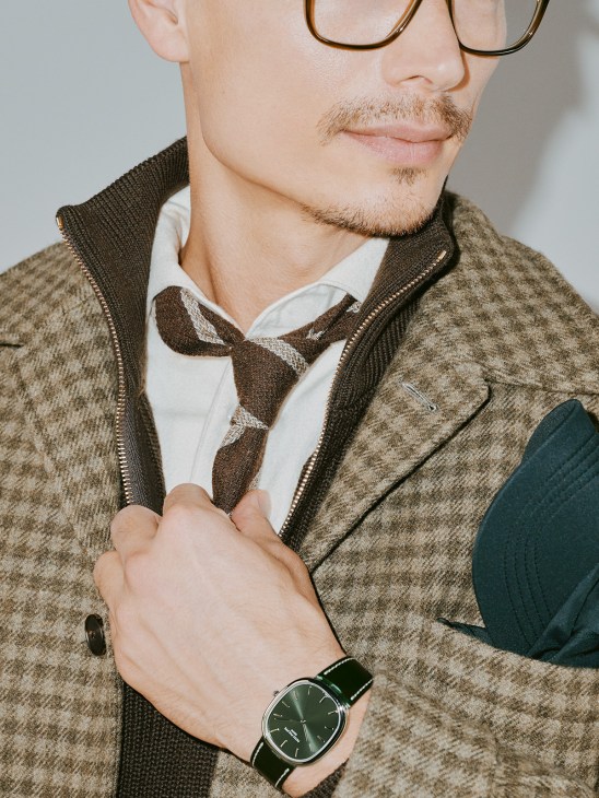 Man wearing Gieves & Hawkes overshirt and tie with Paul & Shark zip jumper, Mykita glasses, and Patek Philippe golden eclipse watch.