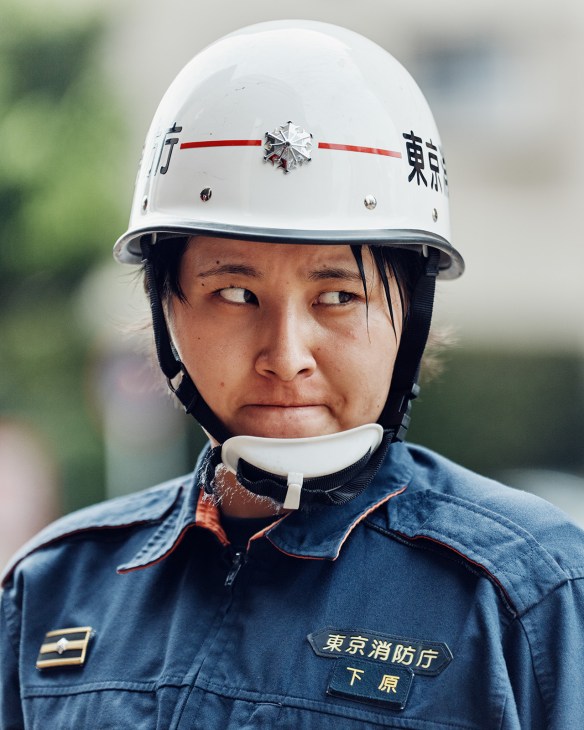 Ayuna Shimohara, 24, a firefighter at Ikebukuro Fire Station, wearing white helmet with Japanese characters and blue uniform.