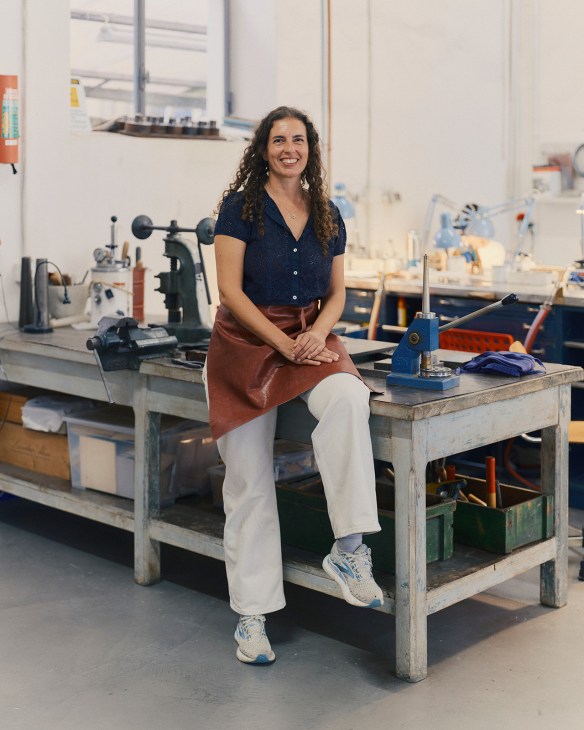 Margherita de Martino Norante smiles while sitting at a workbench in her jewelry workshop at Officine Nora in Florence.