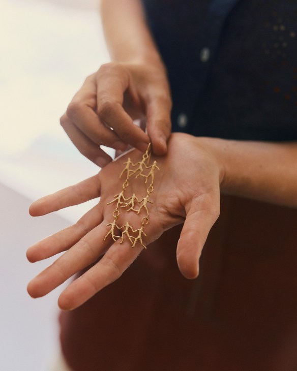 Gold branch-shaped earring displayed in an open palm at Officine Nora jewelry workshop in Florence.