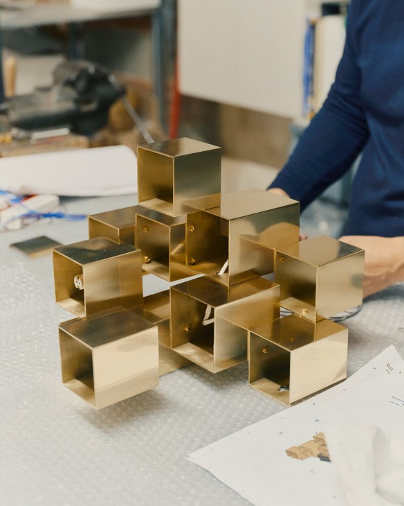 Brass lamp components assembled on a workbench at Bronzetto workshop in Florence.