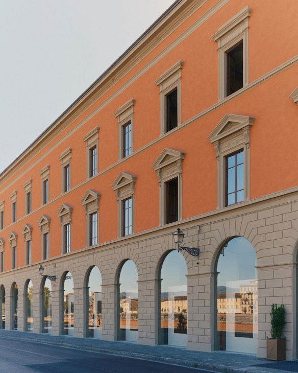 Restored 19th-century terracotta building with arched ground-floor colonnade and rows of rectangular windows along Florence's Arno river.