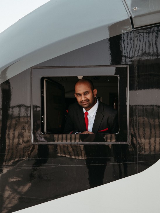Man in black suit with red tie looking out of Etihad Rail train window