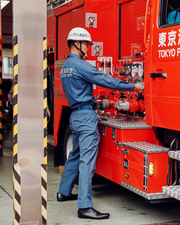 Tokyo Fire Department driver Shoki Yamada checks water-pressure gauges on a red pump truck during morning inspections.