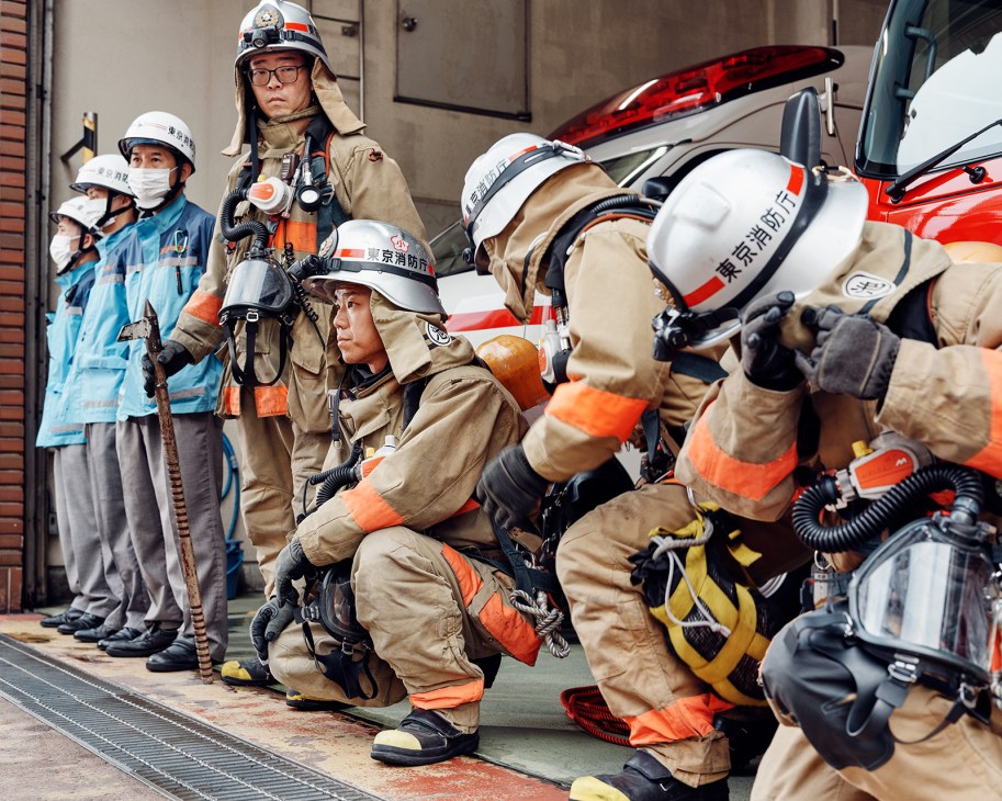 Tokyo Fire Department firefighters in full gear lined up at the fire station.