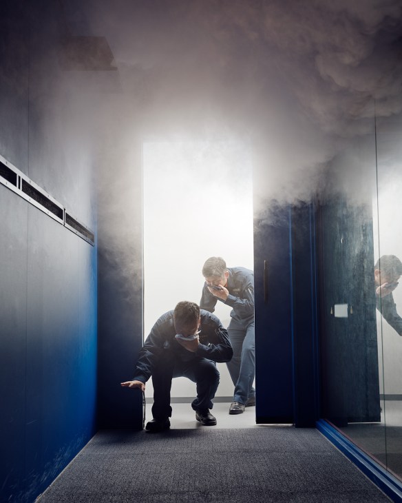 Firefighter trainee crouching and exiting a smoke-filled room during training at Honjo Life Safety Learning Centre