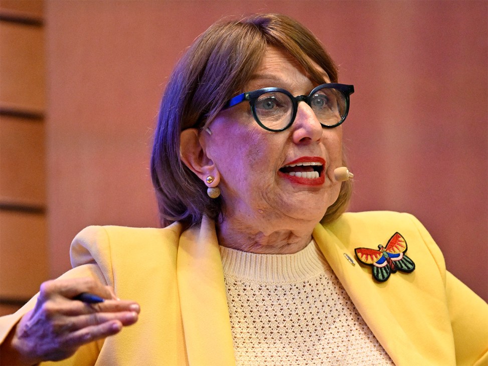 Rebeca Grynspan wearing yellow blazer and glasses speaks passionately during presentation.