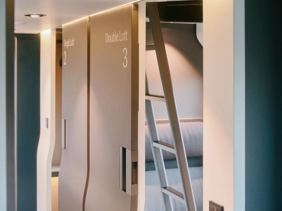 Interior of a Nox sleeper train carriage with two-level cabin bunk beds and a ladder for accessing upper bunks.