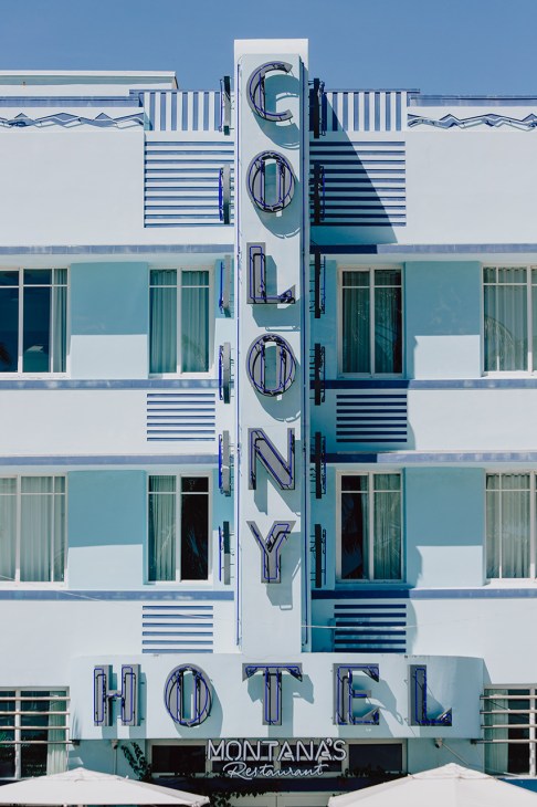 The Tiffany Hotel facade in Miami South Beach with turquoise and white striped art deco design and illuminated neon signage.