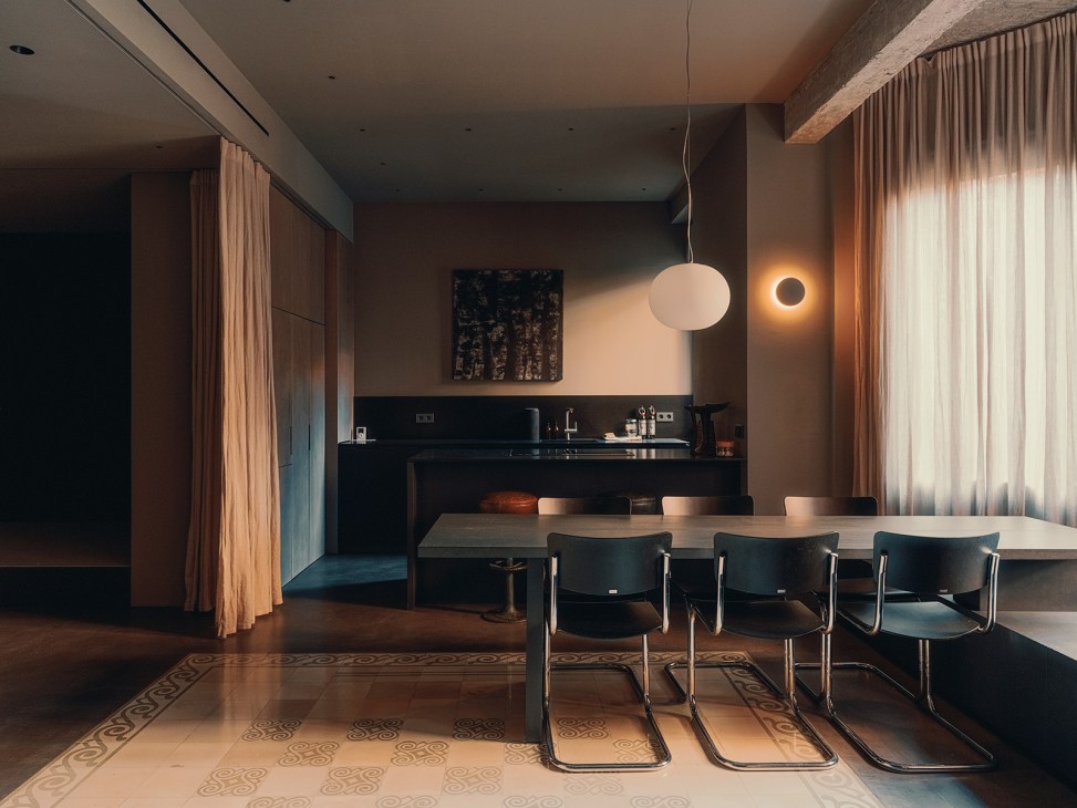 Modern kitchen with black cabinetry, pendant lighting, and dining table with black chairs in Ana Botella Espacio and Philipp Köpfli's Finca Roja apartment.