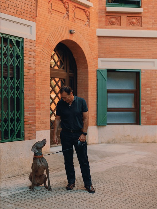 Man in black shirt walks with dog on leash in brick patio courtyard of Finca Roja housing complex.