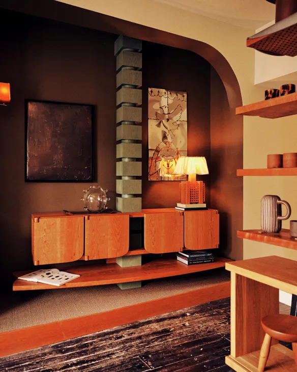 Mid-century modern interior with wooden furniture, warm lighting, and artwork in Piscina's showroom.