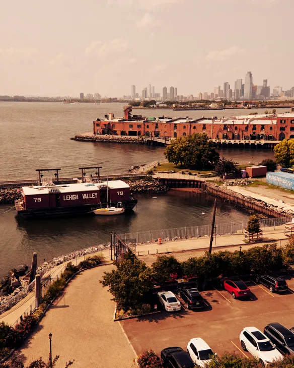 Red brick Waterfront Museum barge docked in Red Hook with Manhattan skyline beyond