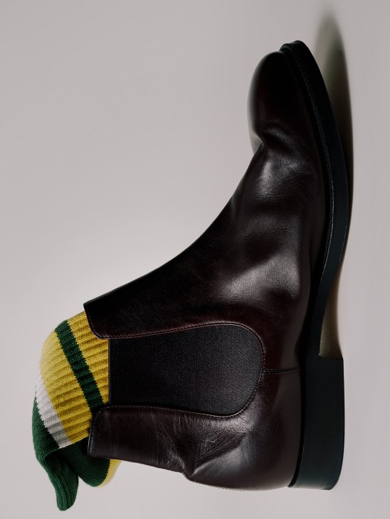 Black leather Chelsea boot with green and yellow striped sock detail by Church's.
