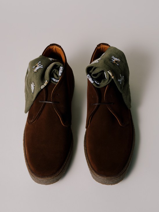 Brown suede desert boots with olive green socks featuring white patterns, displayed from above.
