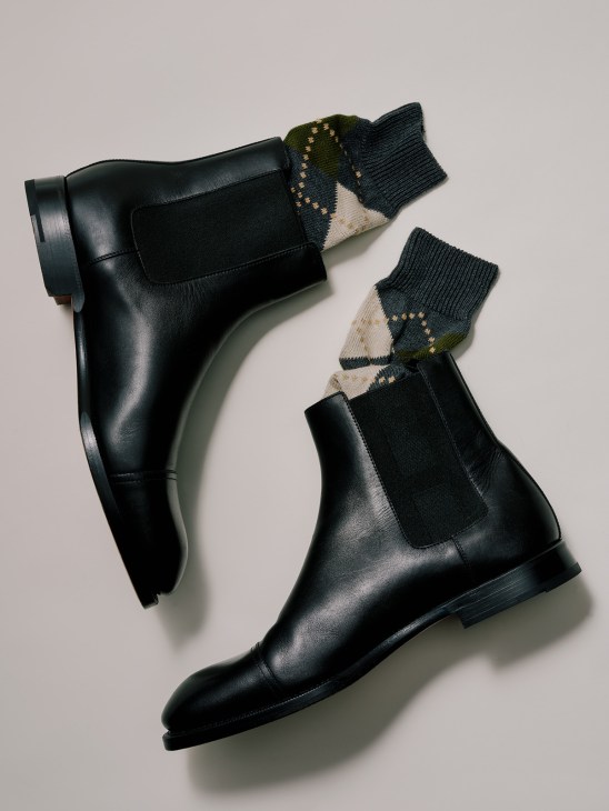 Black leather Chelsea boots by Hermès styled with patterned socks by Ant45 featuring cream, black and olive tones.