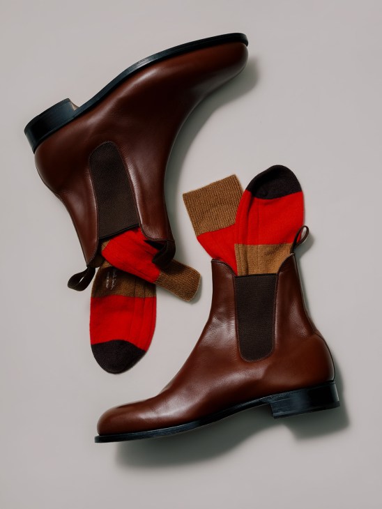 Brown leather Chelsea boots with black trim styled with red, tan and black striped socks.