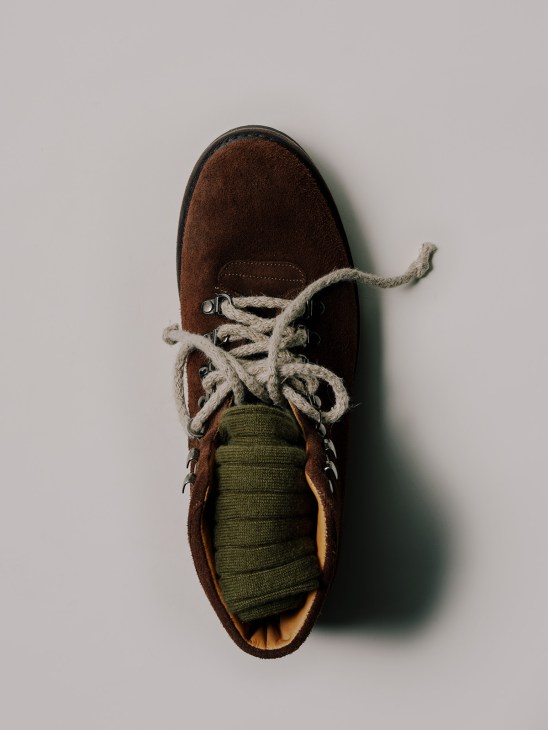 Brown suede boot with rope laces and olive-green socks by Johnstons of Elgin, shown from above.
