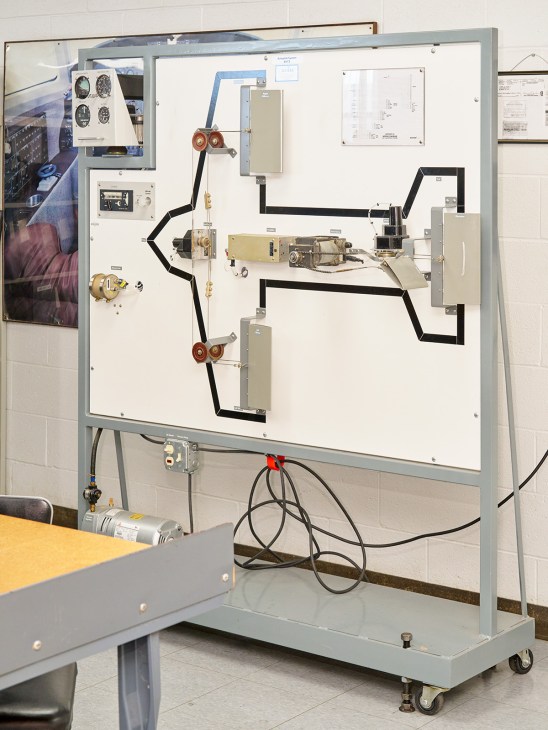 Aviation electronics training board with mounted components, wiring, and technical diagrams on white panel.