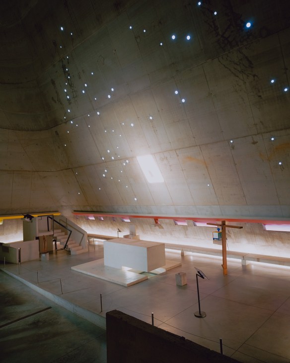 Interior of Église Saint-Pierre with blue lights on coffered ceiling and wooden benches below.