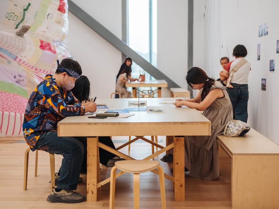 Children and adults engage in art activities at tables in a bright, modern museum gallery space.