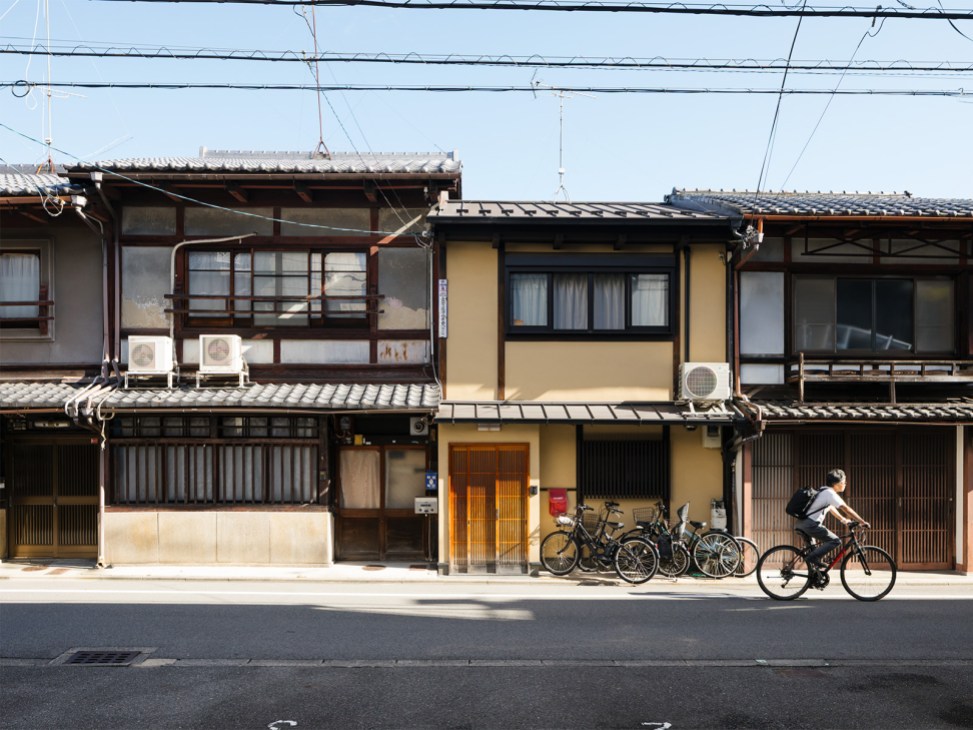 Row of traditional Japanese wooden buildings with modern bicycles parked in front on a Kyoto street.