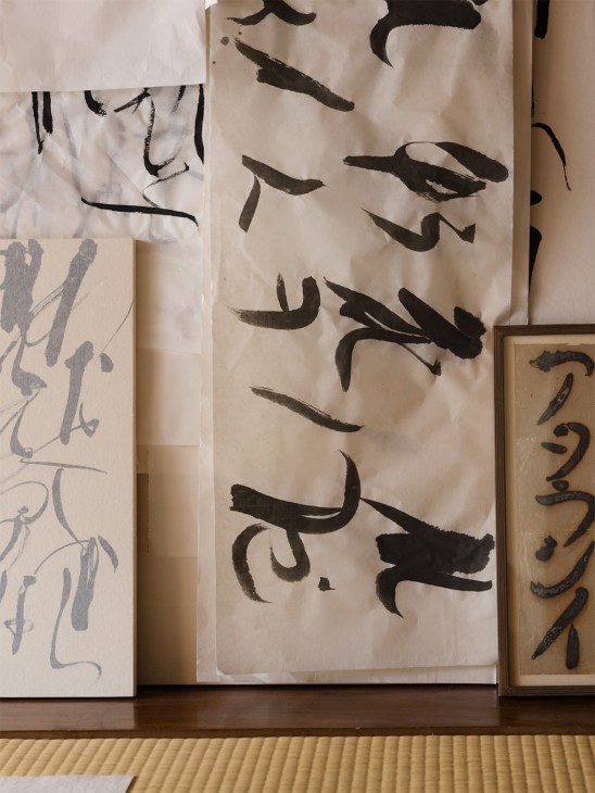 Calligrapher Mikiko Kayama's black ink brushstrokes on cream-colored paper and foil materials.