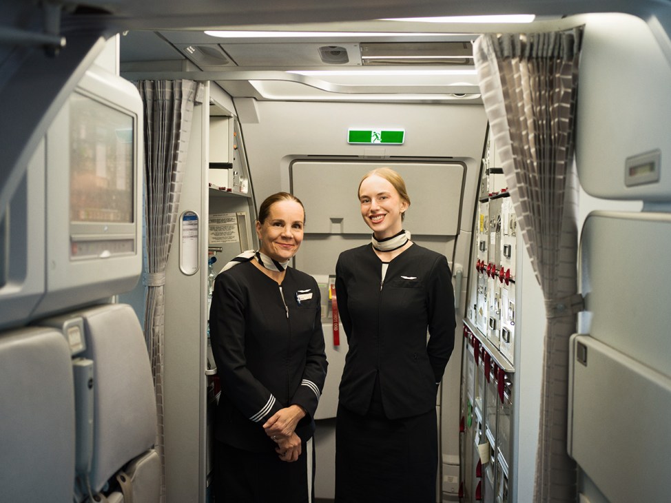 Two Finnair flight attendants in black uniforms standing in an aircraft galley.