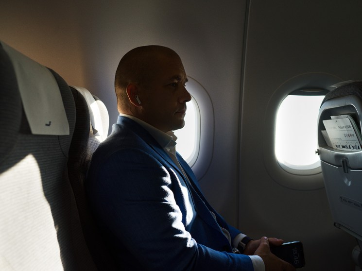 Finnair CEO Turkka Kuusisto sits by an airplane window seat, looking out with a phone in hand during his commute flight.