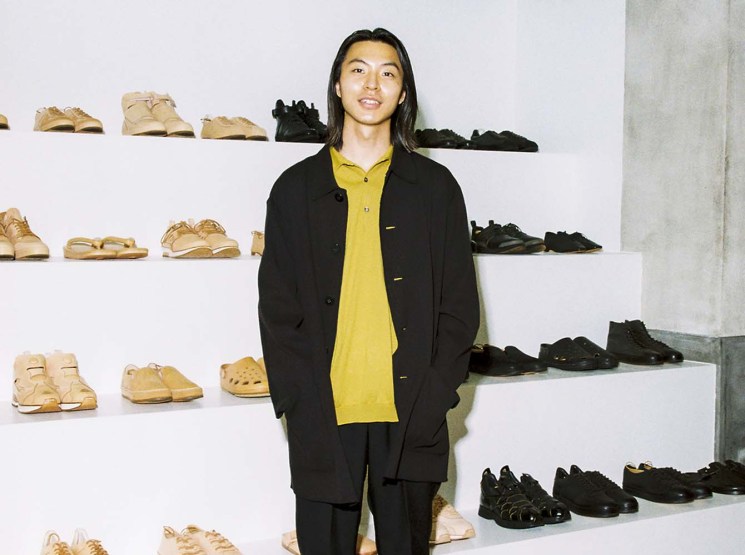 Toga Ikeda standing in Hender Scheme store with shoes displayed on shelves behind him
