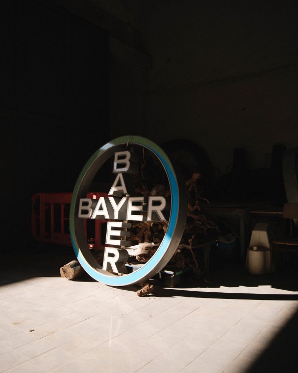 Large neon glasses sign with blue trim sitting on tiled floor in dark warehouse space