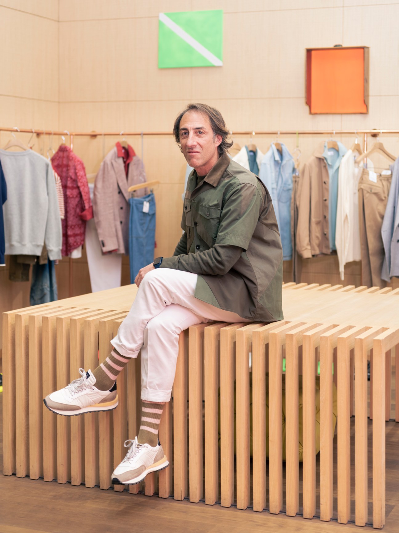 Ludovico Campanini sitting on wooden bench inside The Store Milan with clothing racks in background
