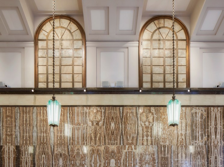 Art deco interior detail showing brass lettering and marble wall fixtures from the original 1940s banking hall design