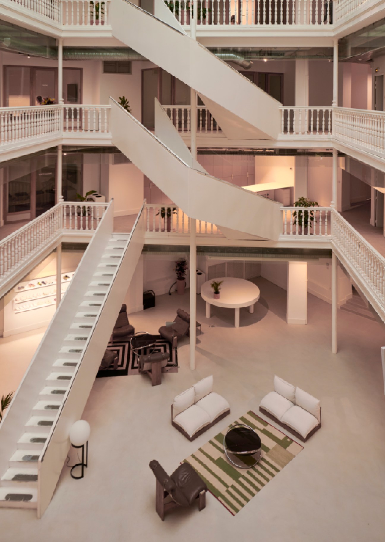 Multi-level modern office interior with white staircases, glass railings, and open atrium design