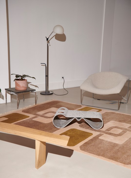 Modern office meeting area with colorful geometric patterned rug, vintage glass coffee table, and ergonomic chair